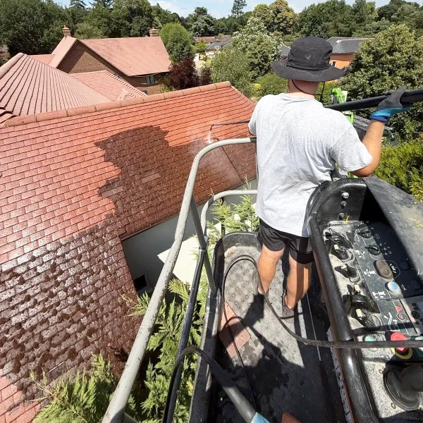 Man cleaning roof from a cherry picker.