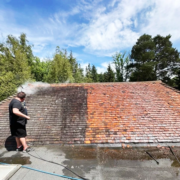 Man halfway through cleaning a roof.