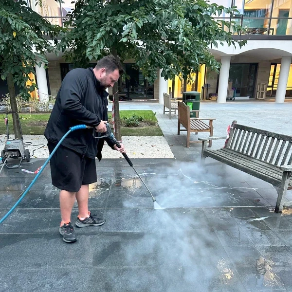 Man pressure washing a slate floor.